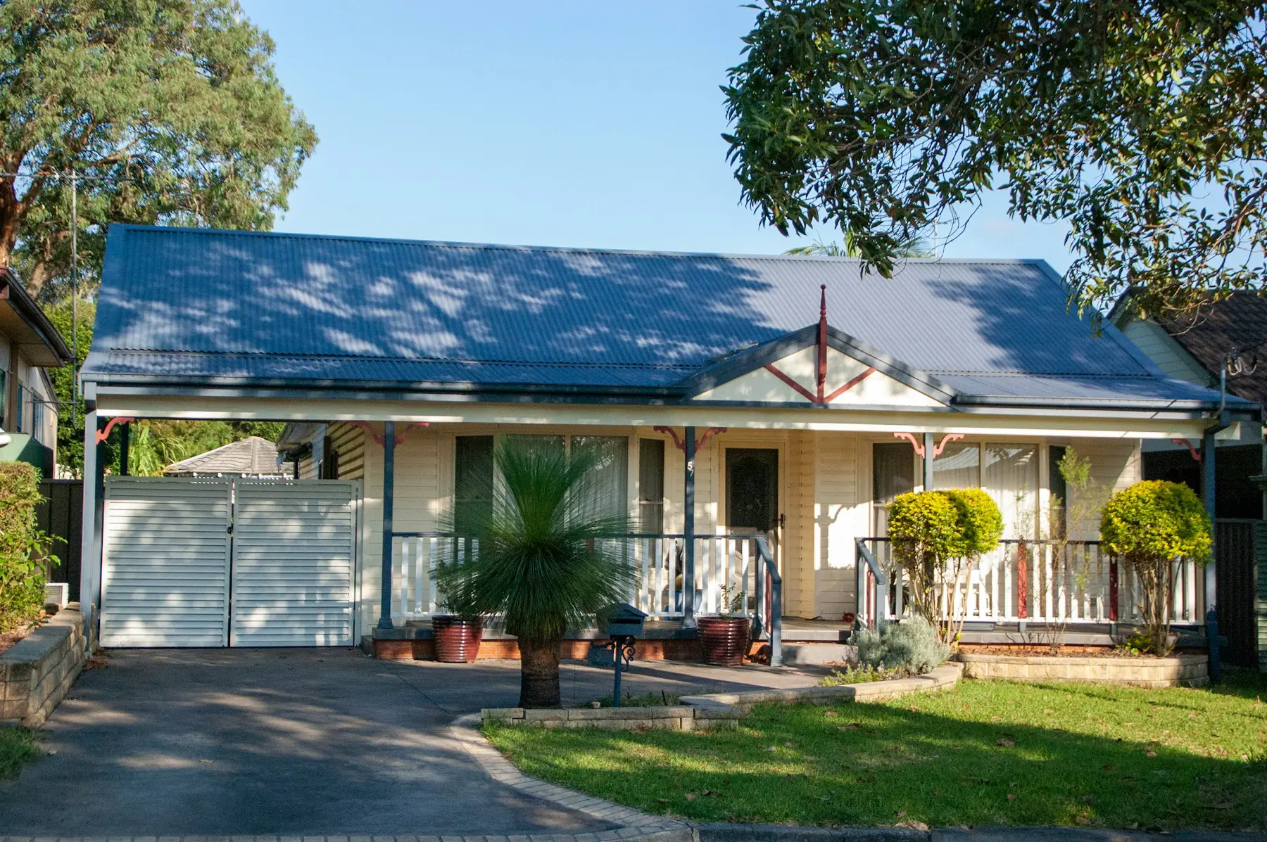 A weatherboard home with a blue roof and a front garden